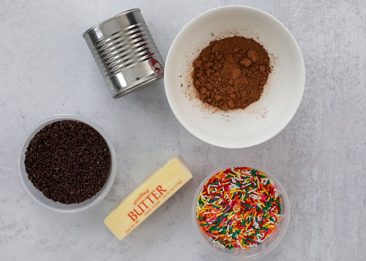 a can of sweetened condensed milk, cocoa powder, sprinkles, and butter. 