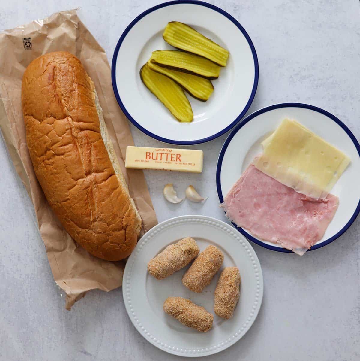 loaf of bread, ham croquettes, ham, swiss, pickles, butter, and garlic. 