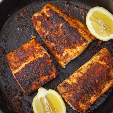 three blackened mahi mahi fillets with lemon wedges on the side.