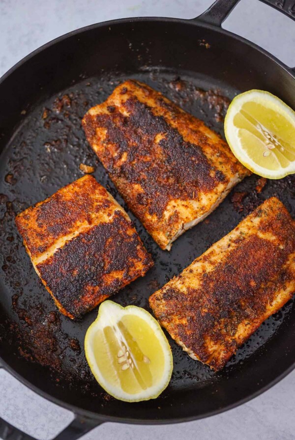 three blackened mahi mahi fillets with lemon wedges on the side.