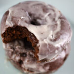 two chocolate glazed donuts on a plate.