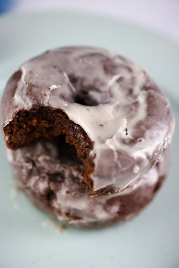 two chocolate glazed donuts on a plate.