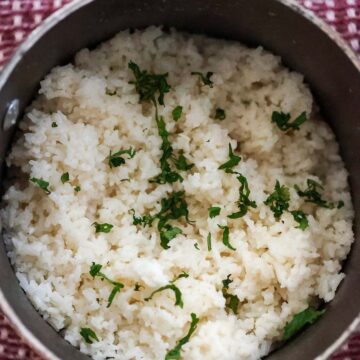 coconut rice in a saucepan with cilantro on top.