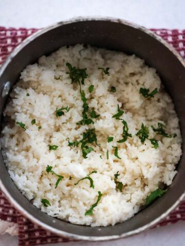 coconut rice in a saucepan with cilantro on top.