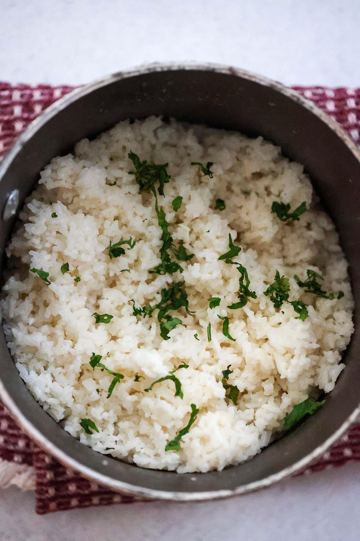 coconut rice in a saucepan with cilantro on top. 