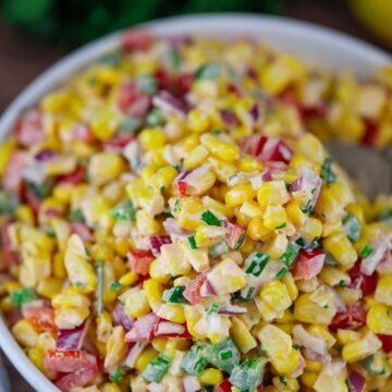 creamy corn salad in a white bowl.