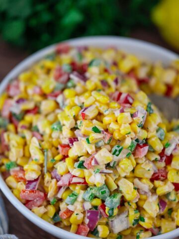 creamy corn salad in a white bowl.