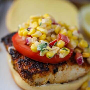 mahi mahi sandwich with corn salad on top.