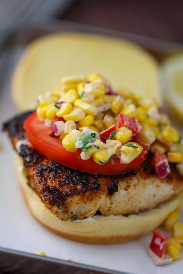 mahi mahi sandwich with corn salad on top.