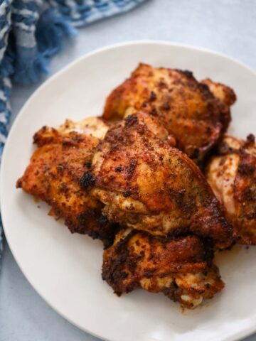 roasted chicken thighs on a white plate.