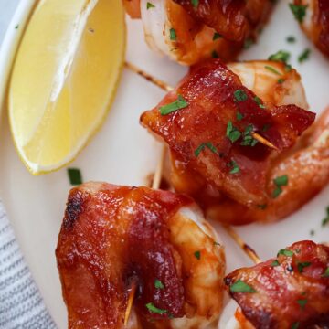 bacon wrapped shrimp with a lemon wedge on the side.