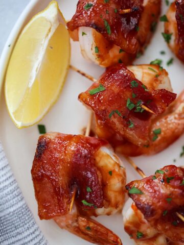 bacon wrapped shrimp with a lemon wedge on the side.