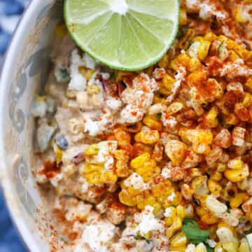 elote corn salad in a bowl with a lime on the side.