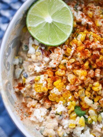 elote corn salad in a bowl with a lime on the side.