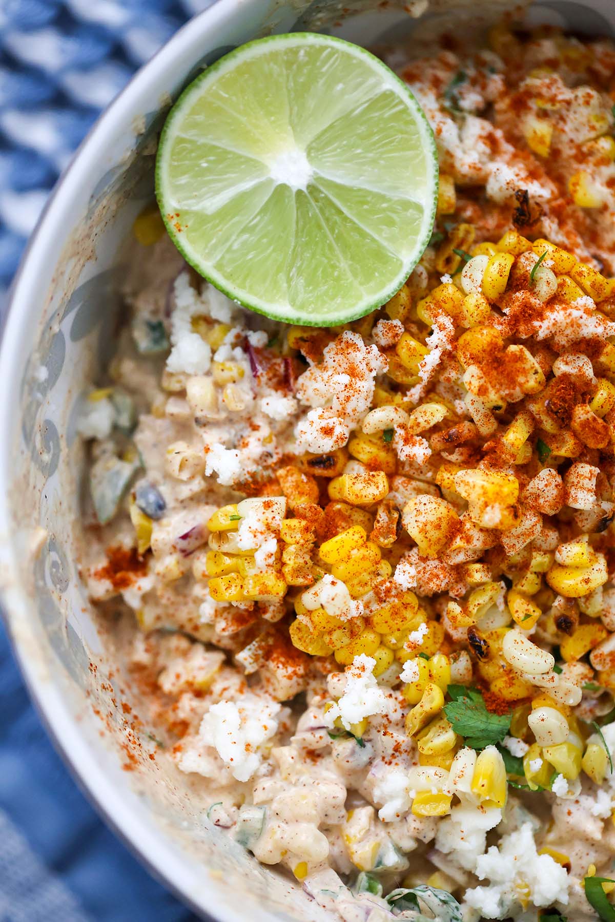 elote corn salad in a bowl with a lime on the side. 