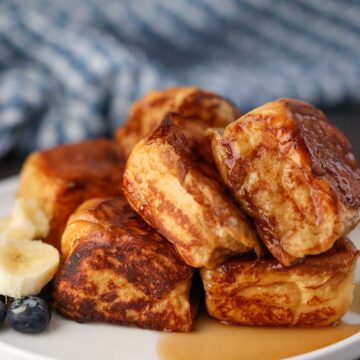 Hawaiian roll French toast with syrup and fruit on the side.