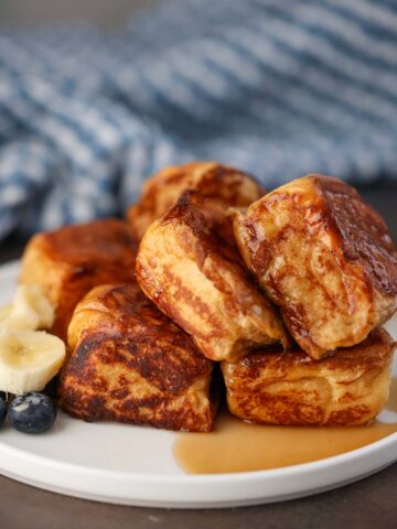 Hawaiian roll French toast with syrup and fruit on the side.