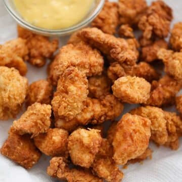 popcorn chicken on a plate with honey mustard on the side.