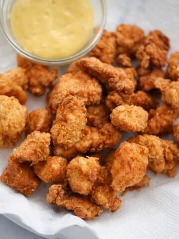 popcorn chicken on a plate with honey mustard on the side.