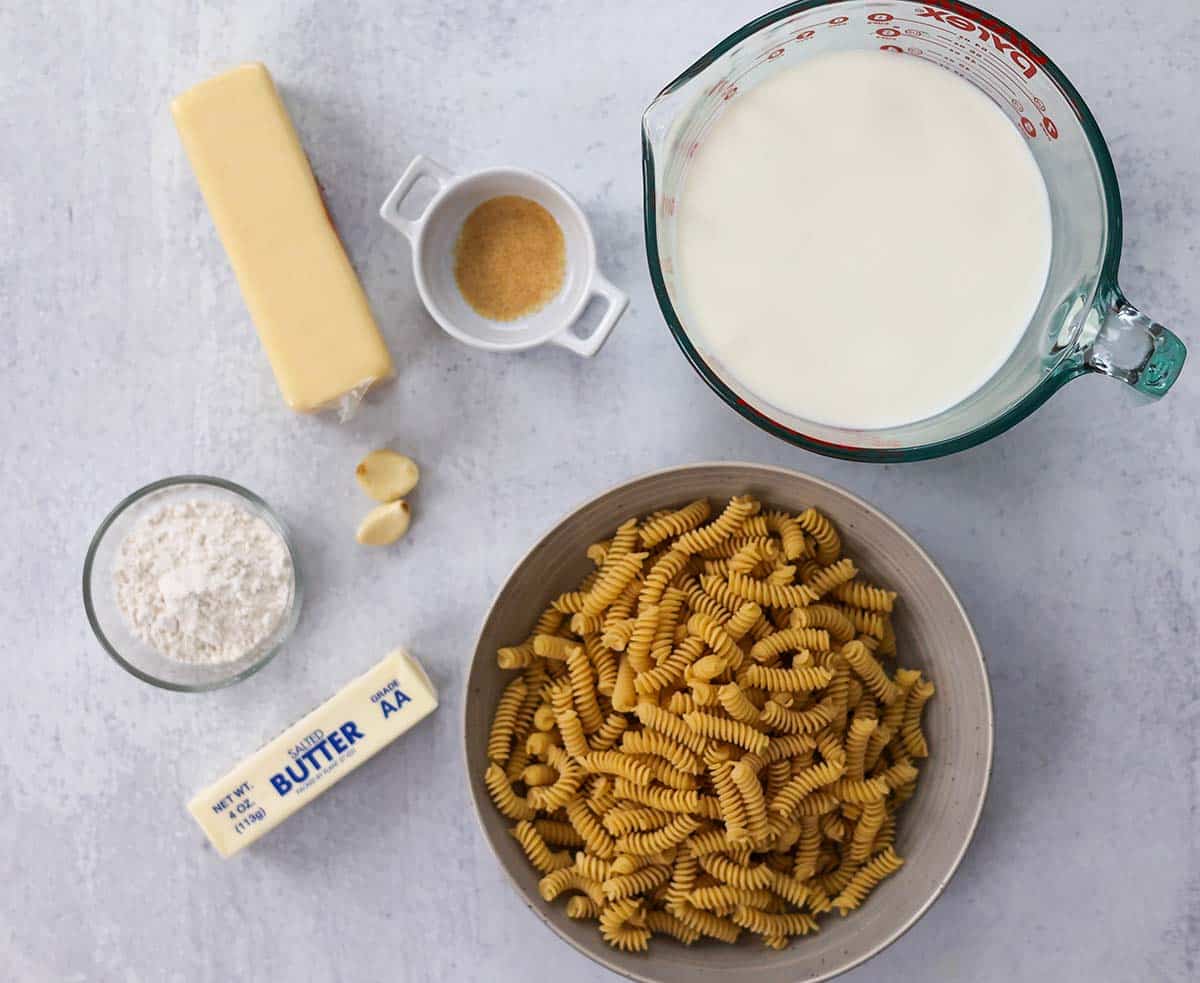 ingredients for white cheddar mac and cheese on a white surface. 