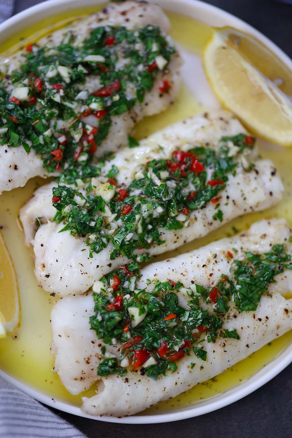 baked cod with chimichurri on a white plate. 