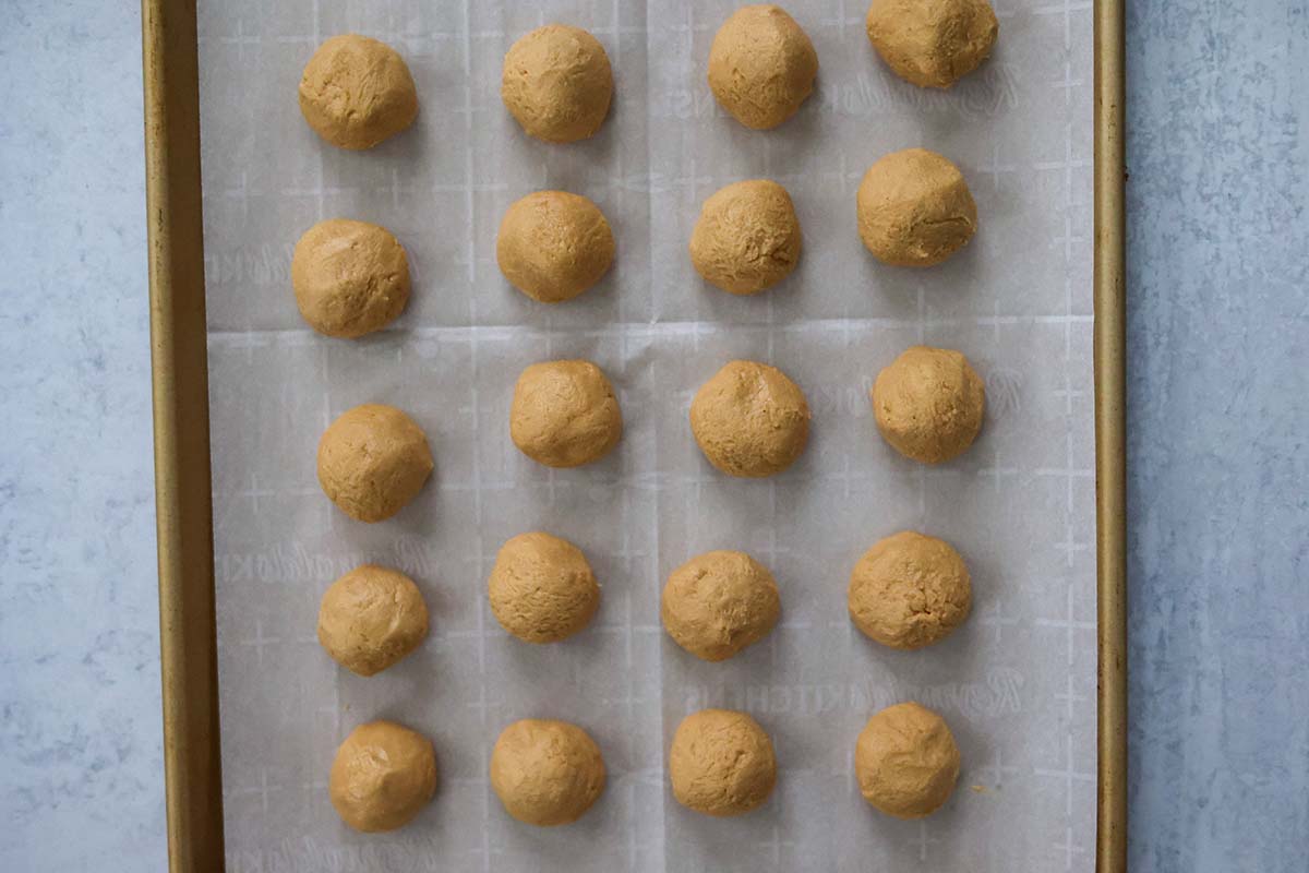 rolled peanut butter balls on a baking sheet. 