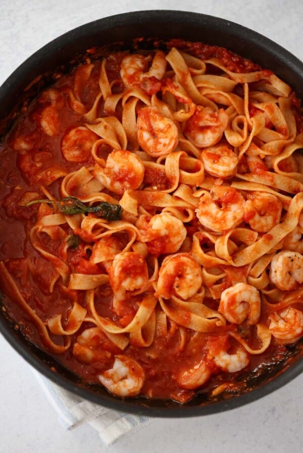 shrimp arrabbiata with tagliatelle in a black skillet.