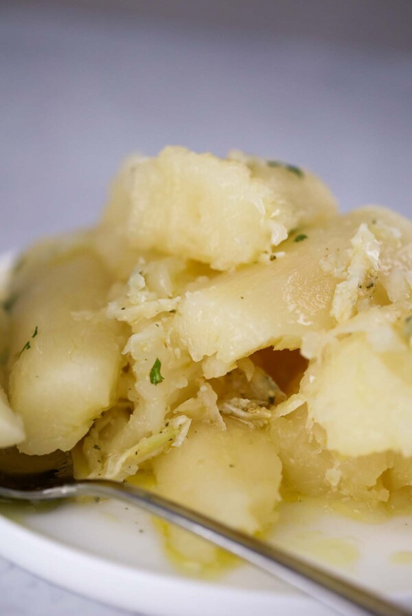 yuca con mojo on a plate with a spoon on the side.