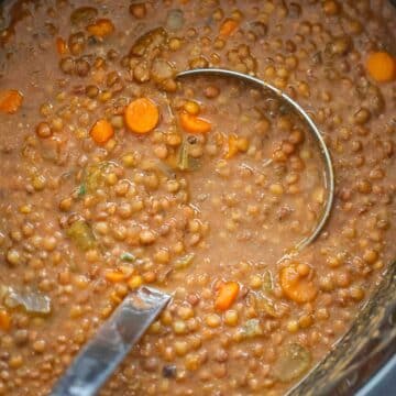 lentil soup in the crockpot with a ladle.