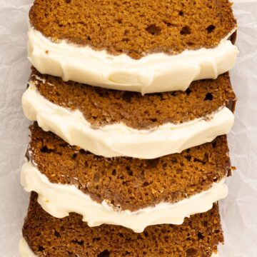 four slices of pumpkin bread with cream cheese frosting.