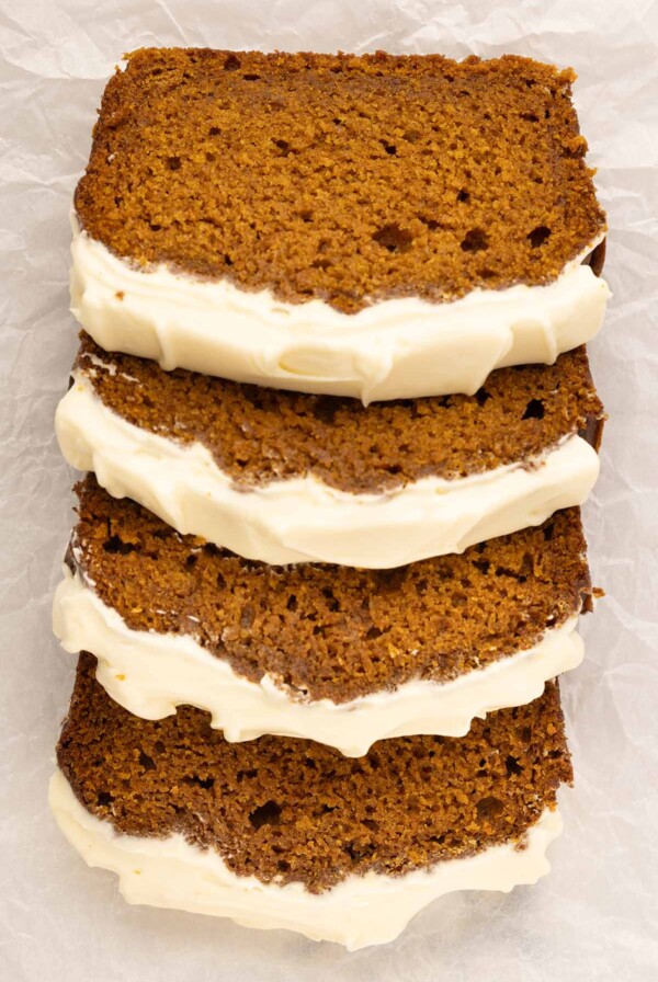 four slices of pumpkin bread with cream cheese frosting.