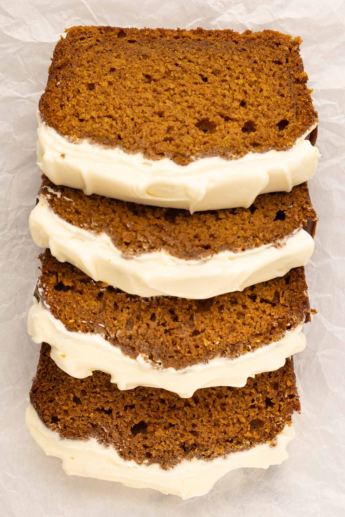 four slices of pumpkin bread with cream cheese frosting. 