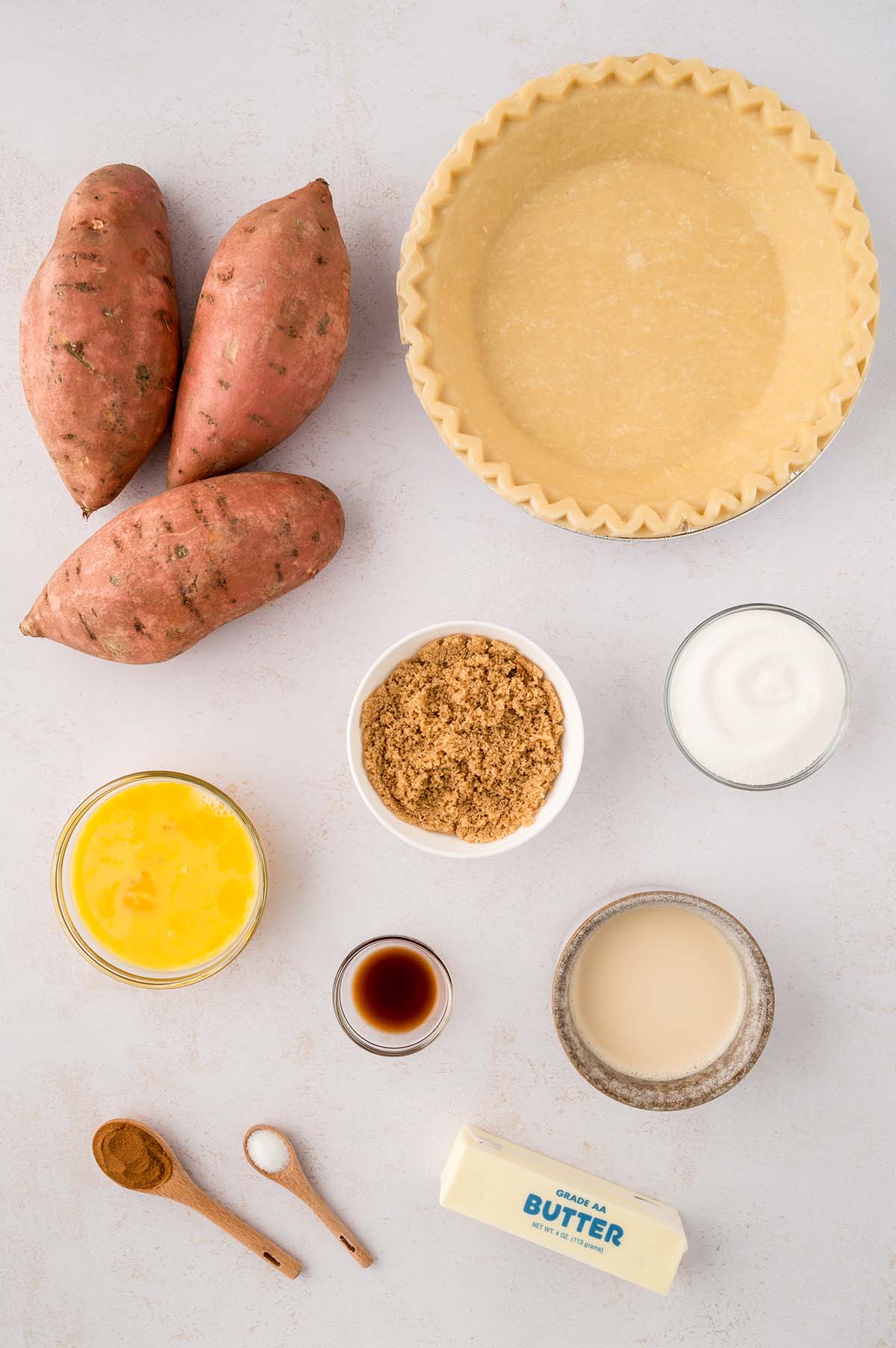 Ingredients for sweet potato pie on a white surface. 