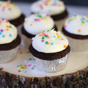 Six chocolate cupcakes with cream cheese frosting and sprinkles.