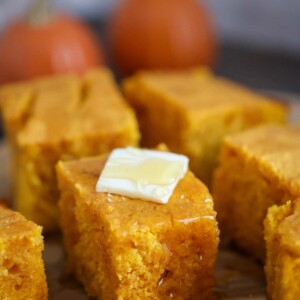 slices of pumpkin cornbread with butter and honey on top.