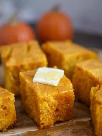 slices of pumpkin cornbread with butter and honey on top.