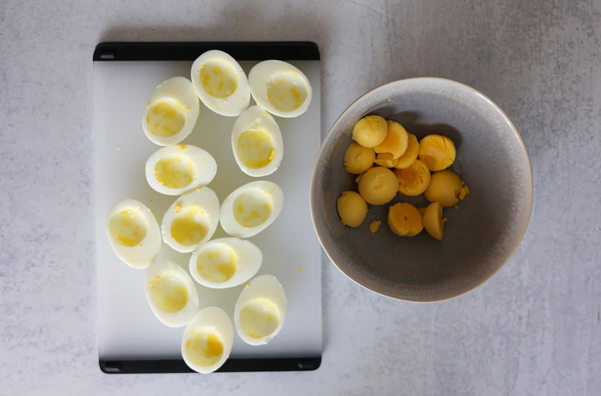 hard boiled egg whites on a cutting board and cooked egg yolks in a bowl. 