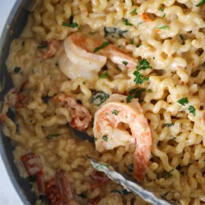 Tuscan shrimp pasta in a skillet up close.