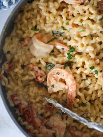 Tuscan shrimp pasta in a skillet up close.