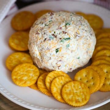 cheese ball on a white plate with crackers.