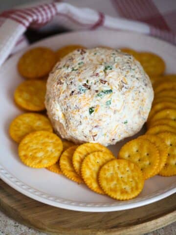 cheese ball on a white plate with crackers.