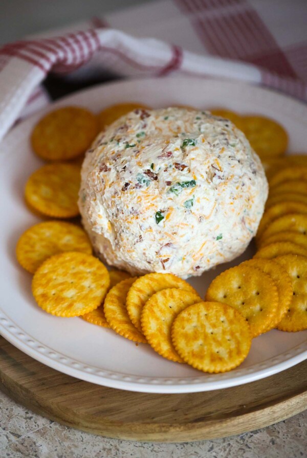cheese ball on a white plate with crackers.