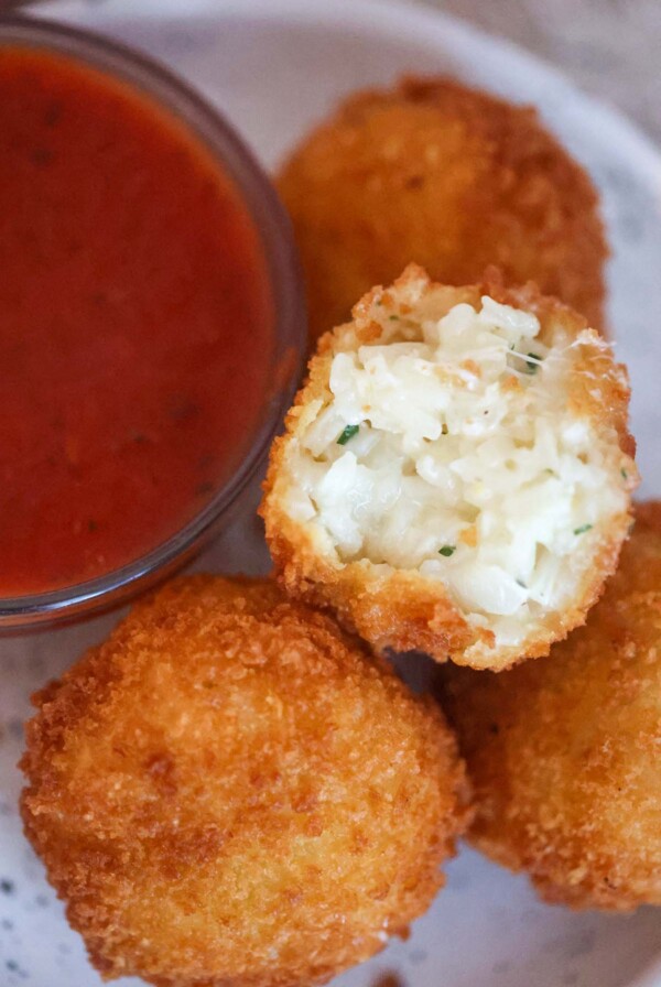 Three cheese arancini with marinara sauce on the side.