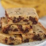 chocolate banana bars on a plate with ripe bananas in the background.