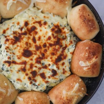 Ultimate spinach artichoke dip with dinner rolls on the side.
