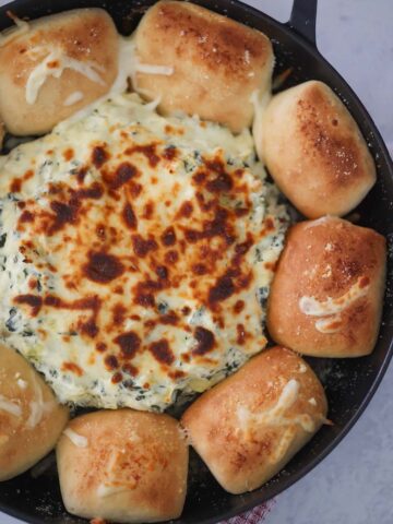 Ultimate spinach artichoke dip with dinner rolls on the side.