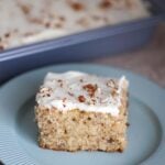 A slice of hummingbird sheet cake on a blue plate.
