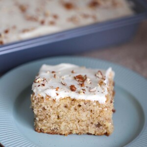A slice of hummingbird sheet cake on a blue plate.