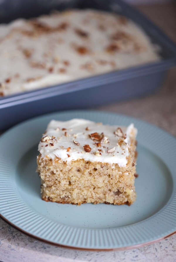 A slice of hummingbird sheet cake on a blue plate.