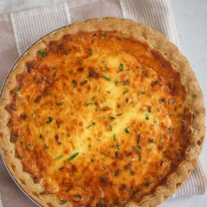 Three cheese quiche on a pink and white towel.